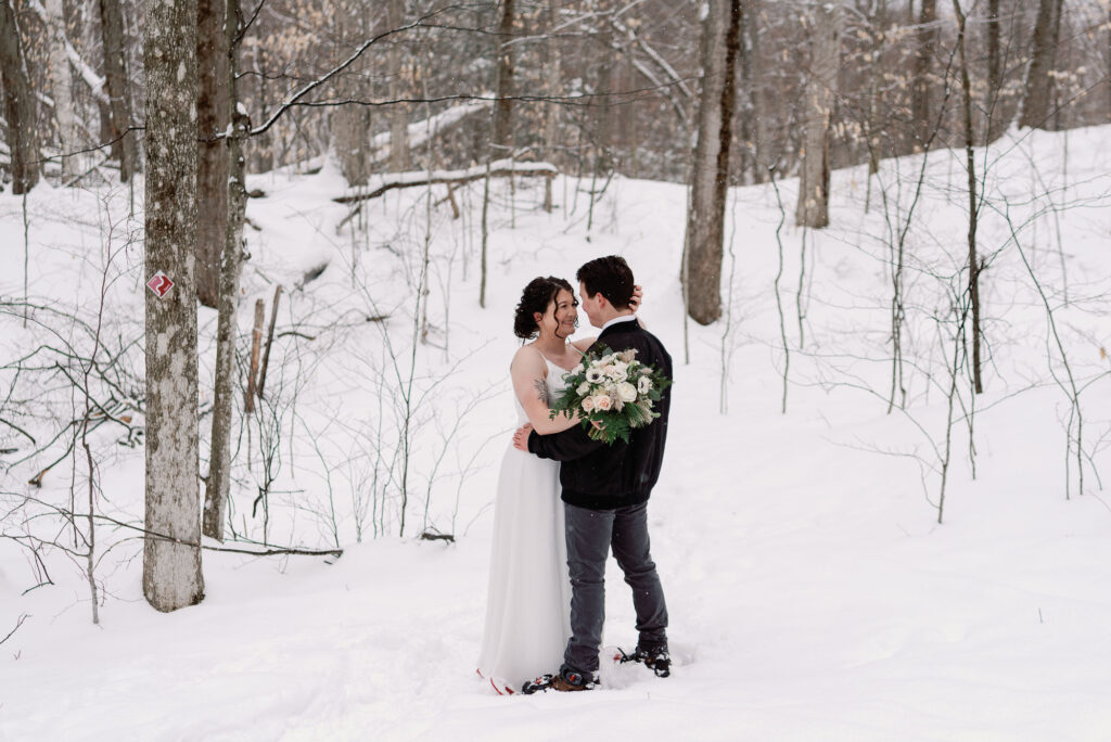 bride and groom walk through winter forest in vermont elopement