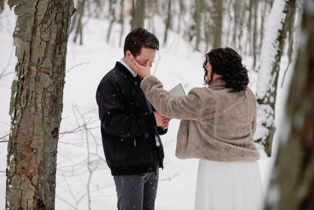bride and groom walk through winter forest in vermont elopement