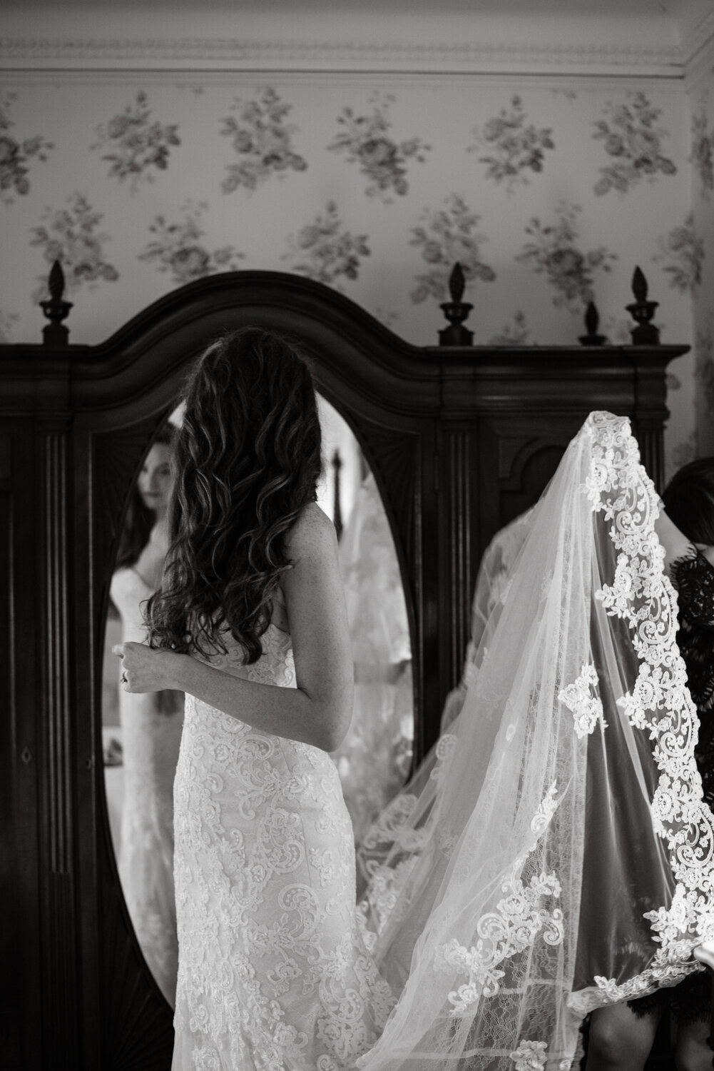 Black and white portrait of a bride getting ready, wearing a lace veil
