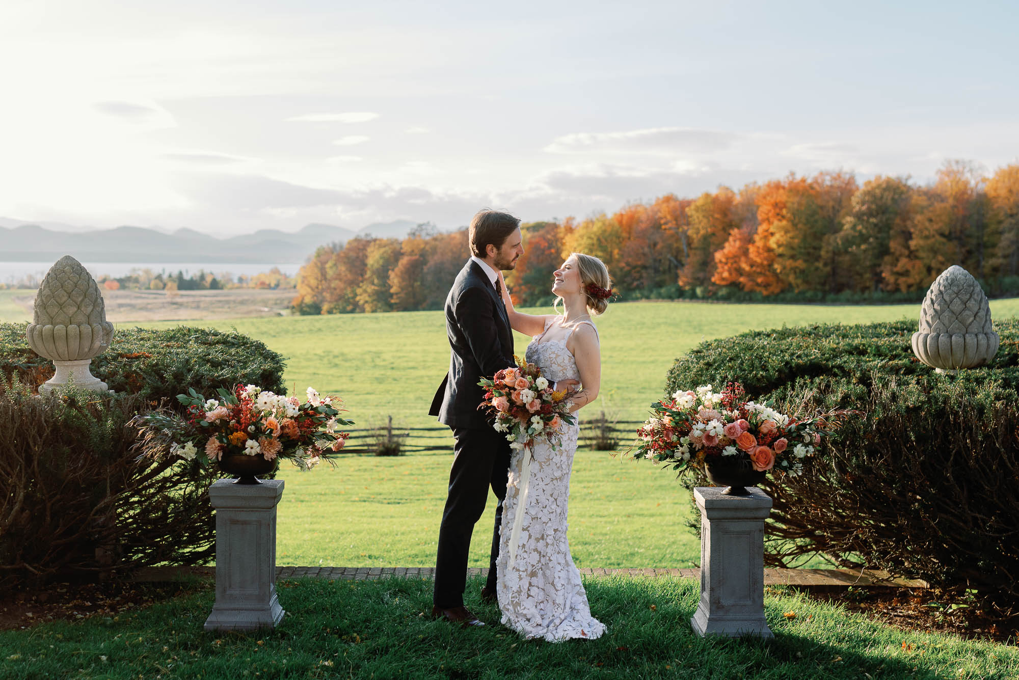 Bride and groom at wedding ceremony surrounded by fall leaves and flowers at the brick house at shelburne museum in vermont