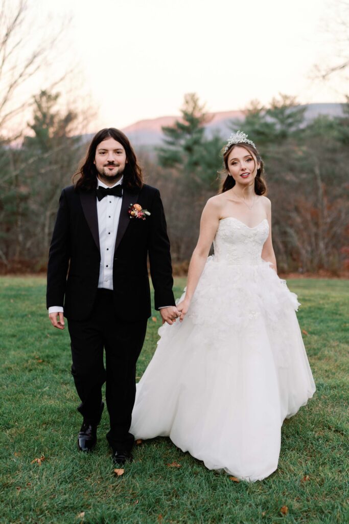 bride and groom walk towards camera in marchesa wedding gown with west mountain inn mountains in the background