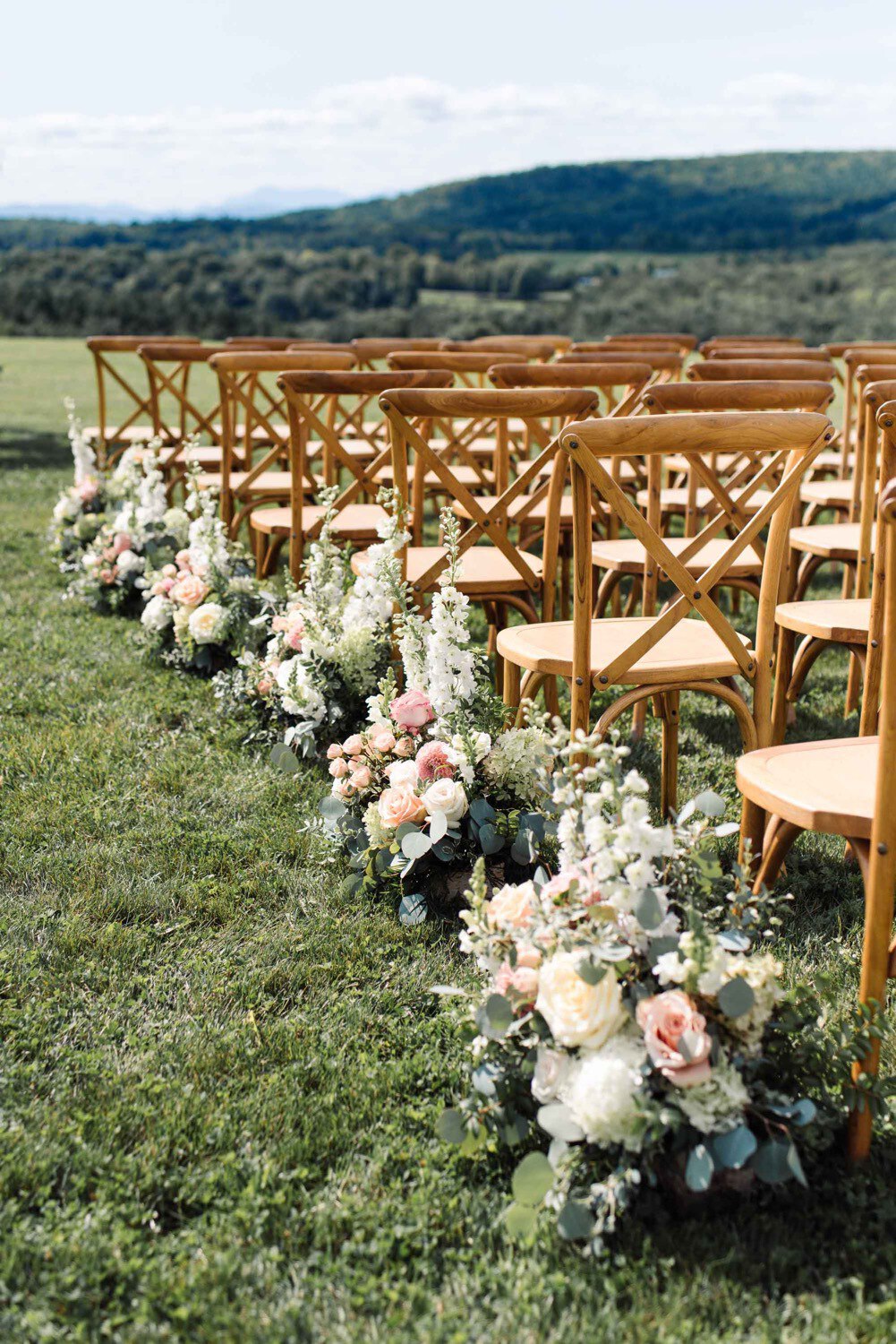 Aisle flower arrangements by Clayton Floral for summer outdoor wedding