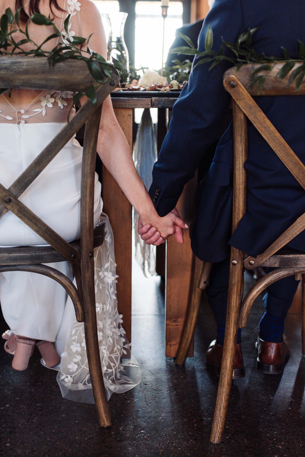 Bride and Groom hold hands surreptitiously at wedding reception