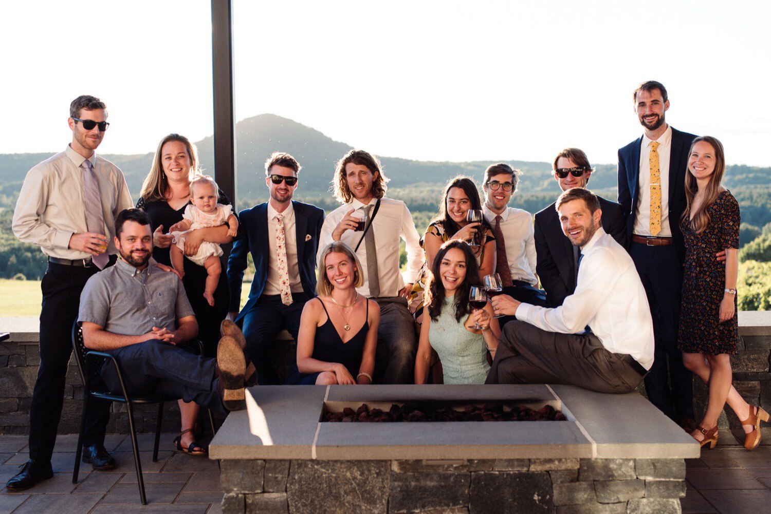 Family and friends pose for photos on patio at summer wedding