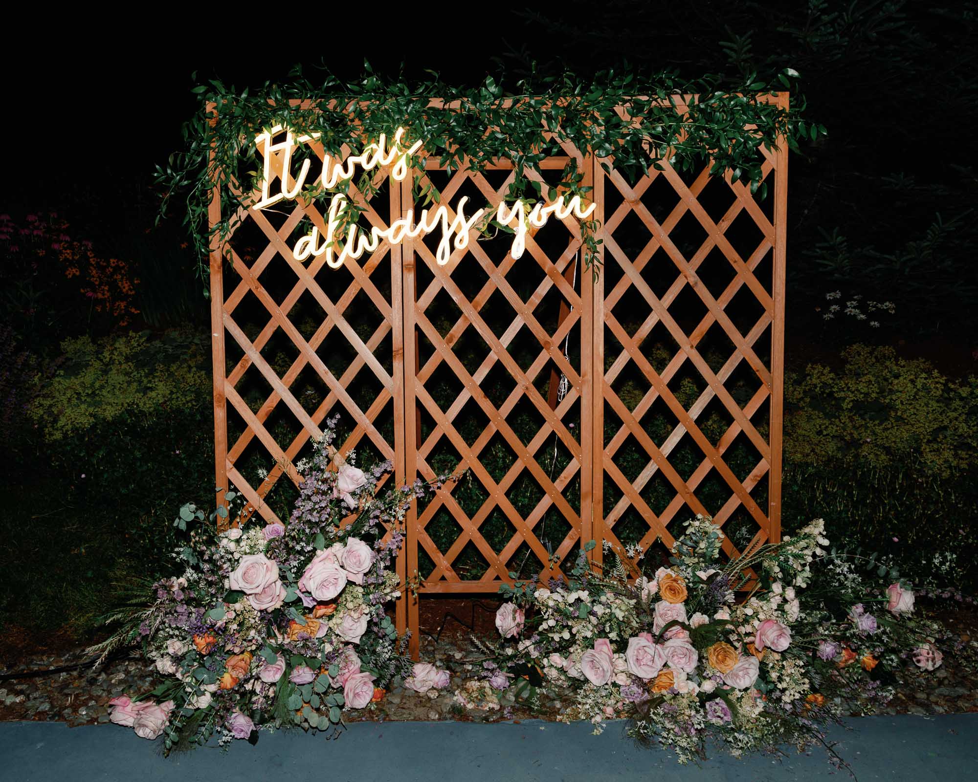 3-panel lattice with floral arrangements, neon light reads "It was always you" - heartfelt guest experience