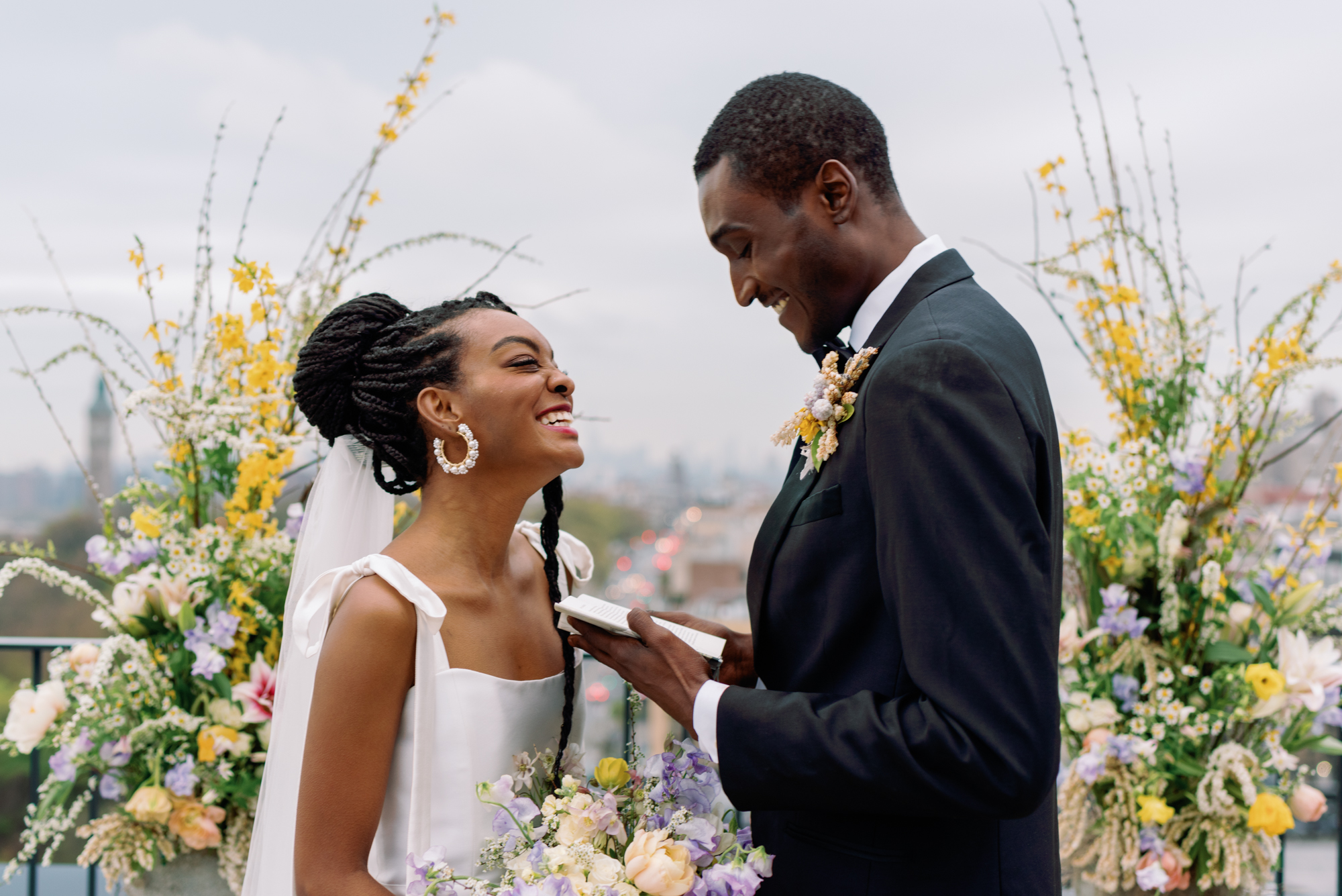 Chic modern wedding couple marries at rooftop nyc ceremony with yellow flowers surrounding them and views of the manhattan skyline