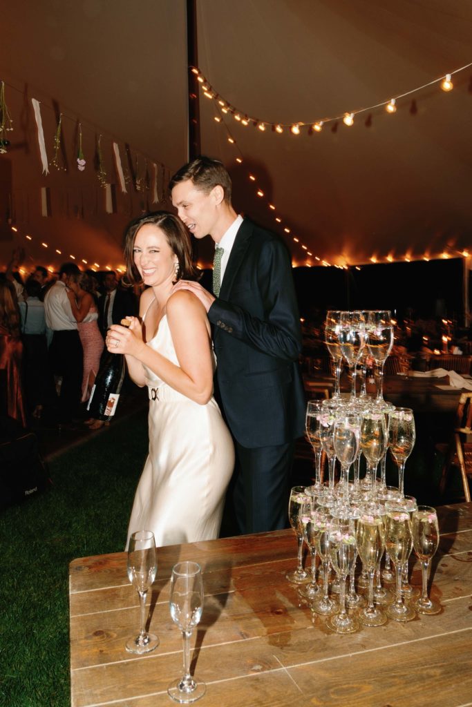 bride pops champagne at wedding with tower of bubbly