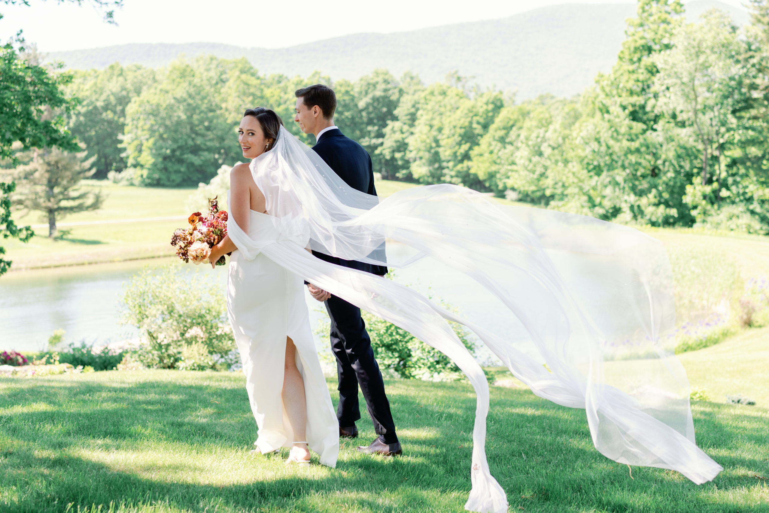 Bride looks back over her shoulder as Sarah Seven gown floats in the wind at Harlow and Dahlia Events wedding in Vermont