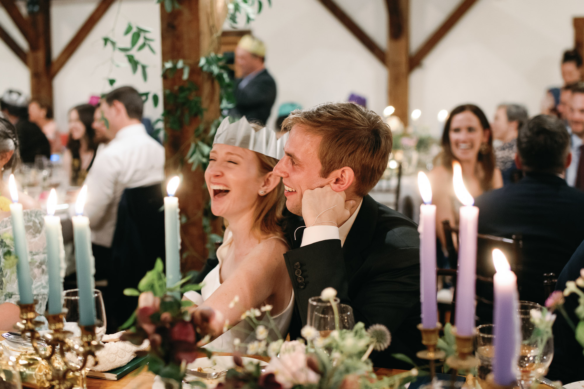 bride and groom laugh at wedding toasts at riverside farm reception barn in vermont