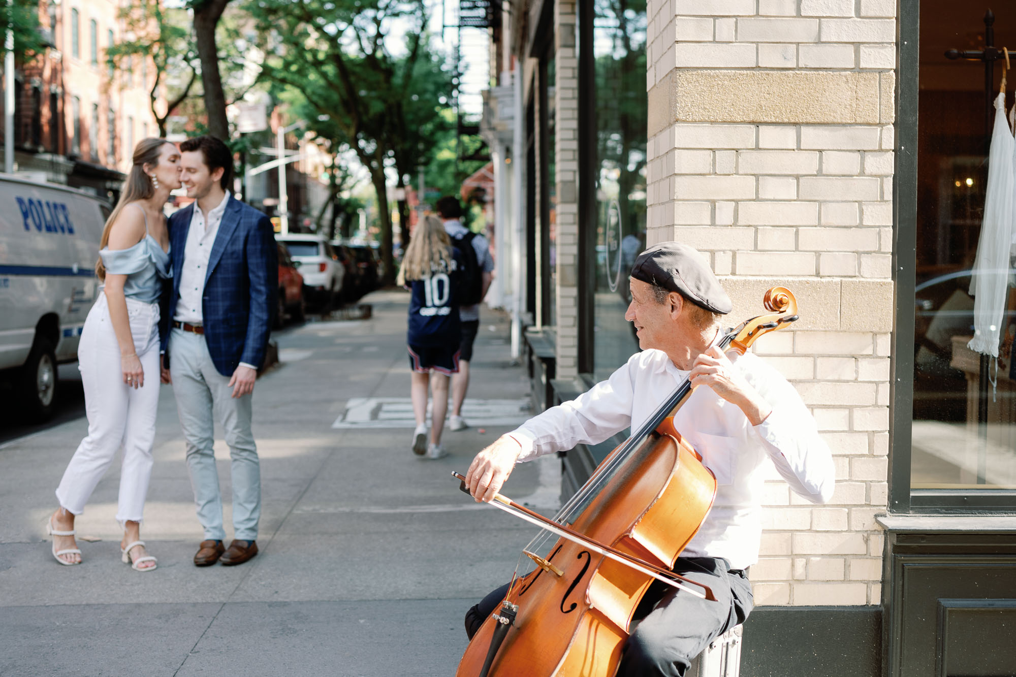 couple kisses in NYC west village engagement session as a cello player plays music