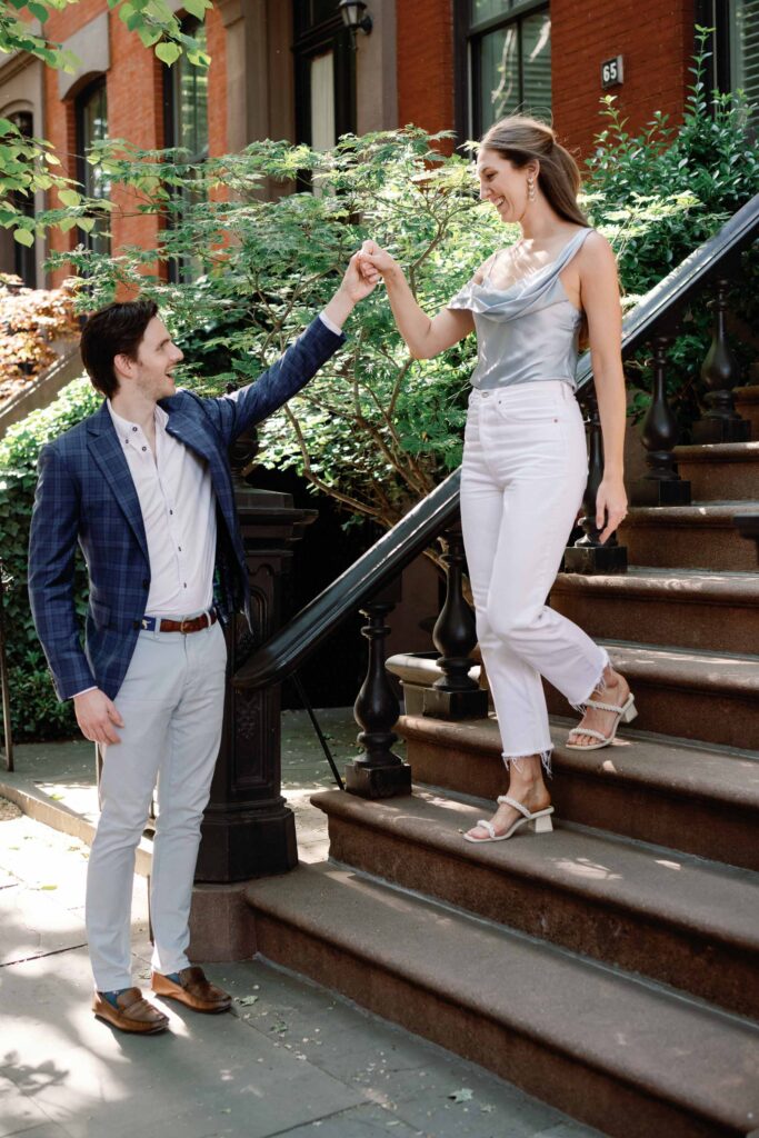 engagement session couple descends stairs in west village nyc in cute engagement outfits