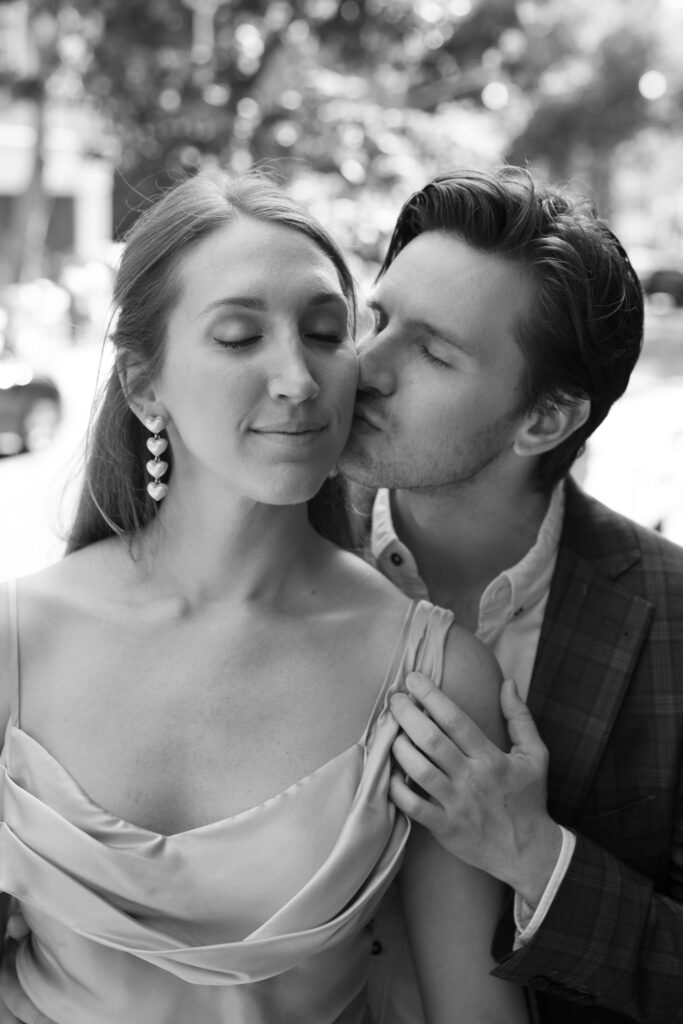 groom kisses bride in oscar de la renta earrings in black and white photo in nyc engagment session