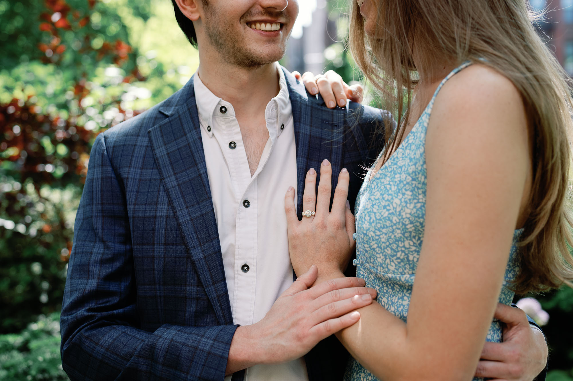 couple embraces with detail photo of andria barbone marielle engagement ring